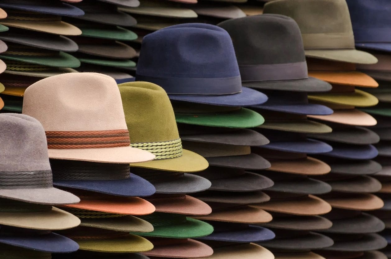 Many different colored Hats are lined up in a row.