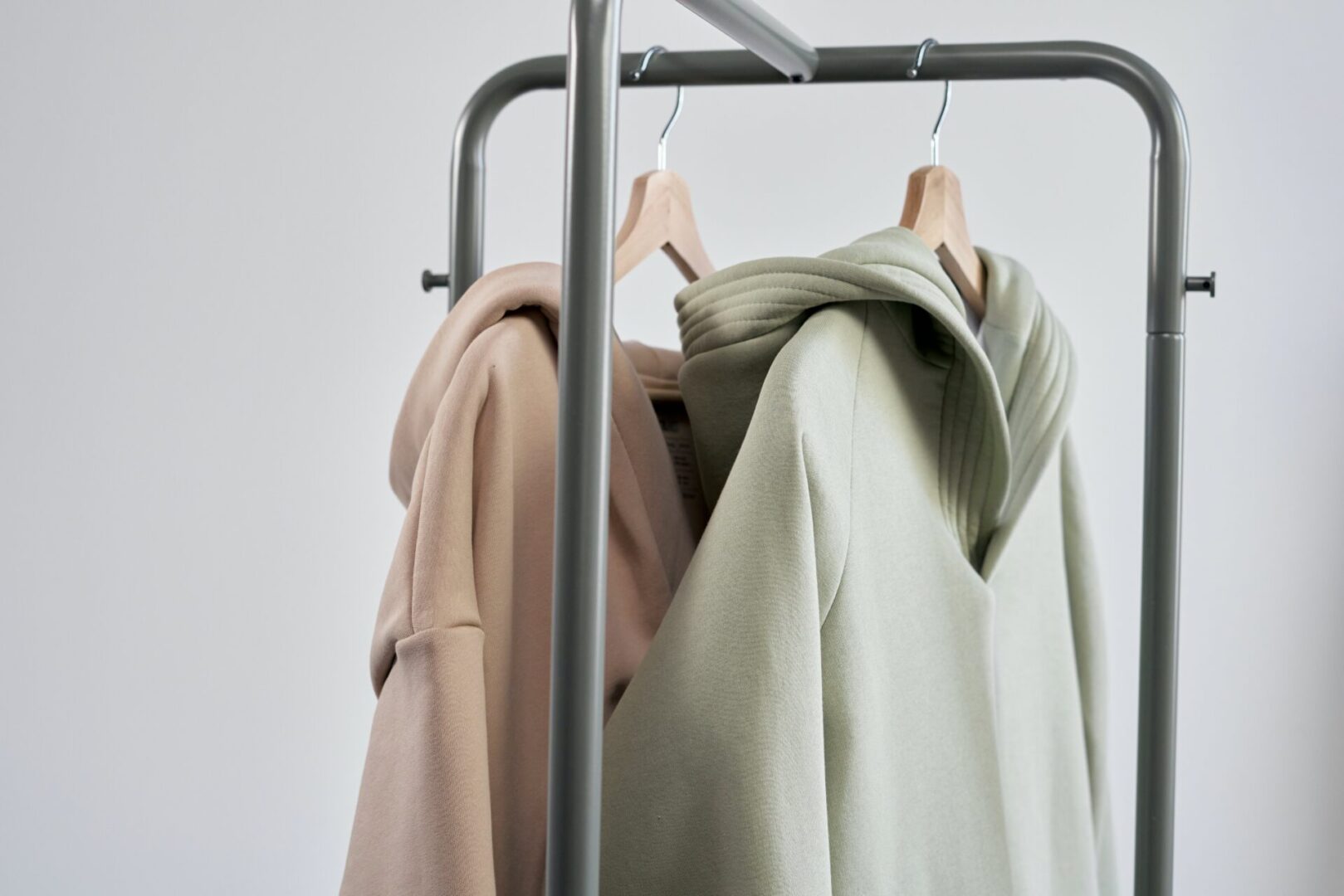 Two sweatshirts hanging on a metal rack.