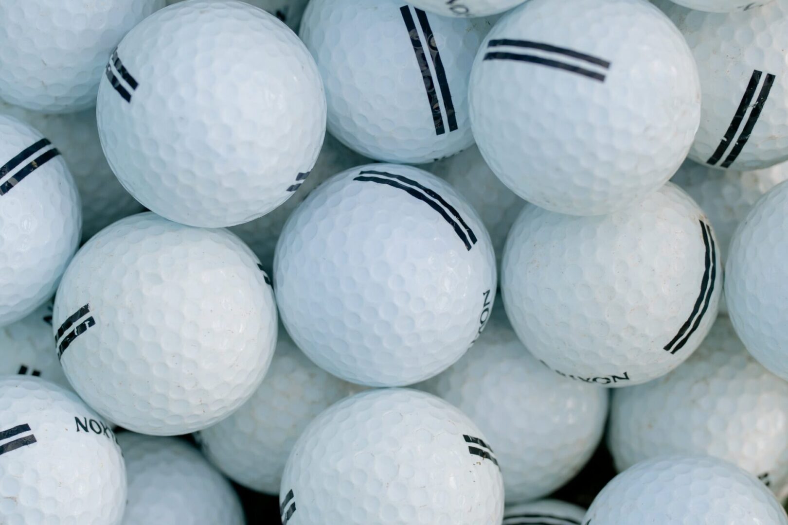 A pile of white Golf Balls with black stripes.