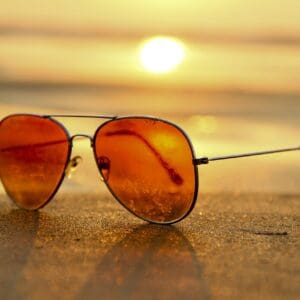 A pair of glasses on the sand at sunset.
