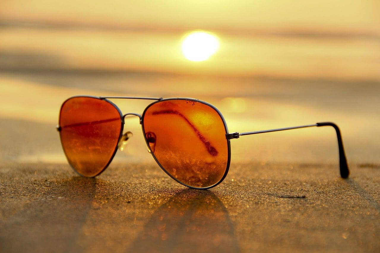 A pair of glasses on the sand at sunset.