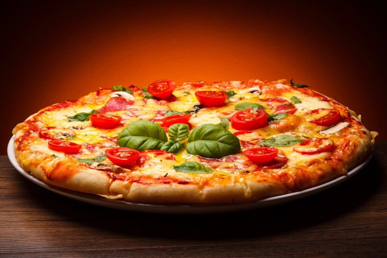 A pizza with tomatoes and basil on a wooden table.