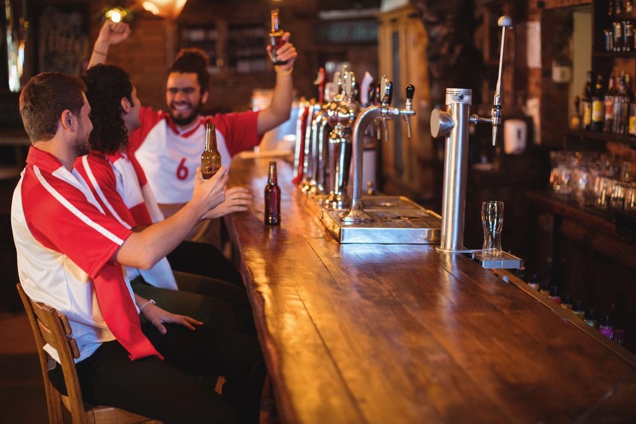 A group of people sitting at a bar and drinking beer.