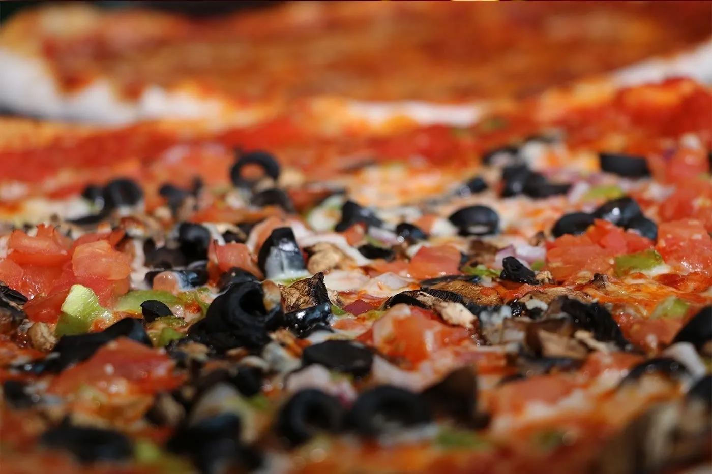 A close up of a pizza with olives and black olives.